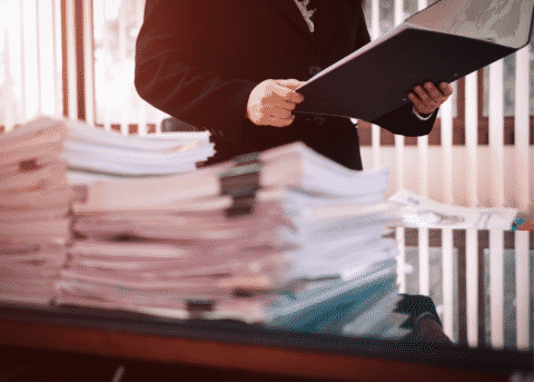 Person looking at stacks of documents on a desk