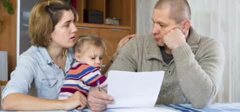 Young family looking at paperwork with worried expression 