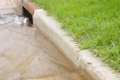 water and trash running down residential street into storm drain