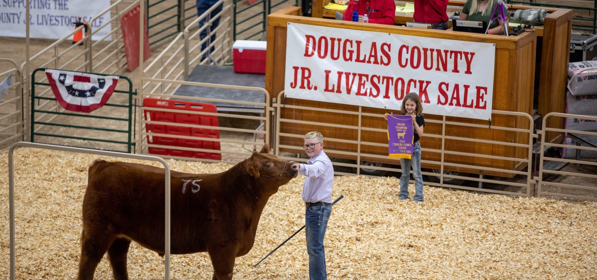 a person and a girl standing next to a cow in a pen
