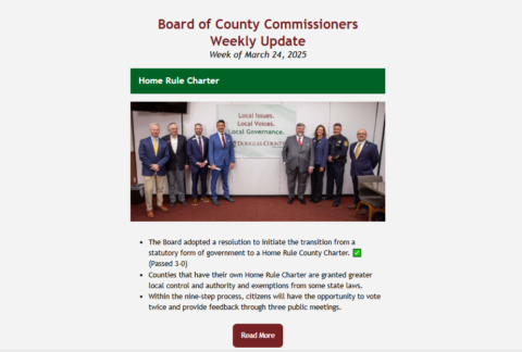 screenshot of email sent each friday with a summary of the Commissioners work the past week. Photo is email shows a group of elected officials standing in front of a sign