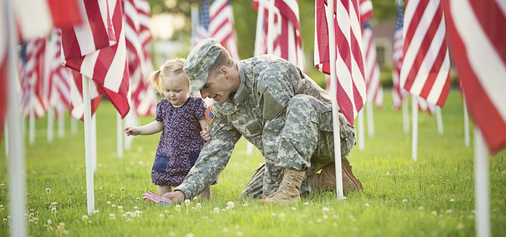 Soldier and daughter placing flag in cemetery